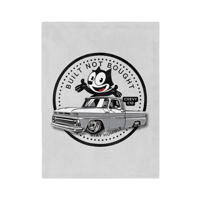 Light grey plush blanket printed with a round Built Not Bought badge, a cartoon cat leaning on a lowered classic pickup truck, with Stay Humble along the bottom.