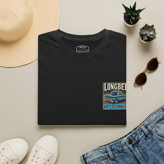Black Longbed t-shirt folded flat beside a straw hat, sunglasses, jeans and white trainers, chest badge showing