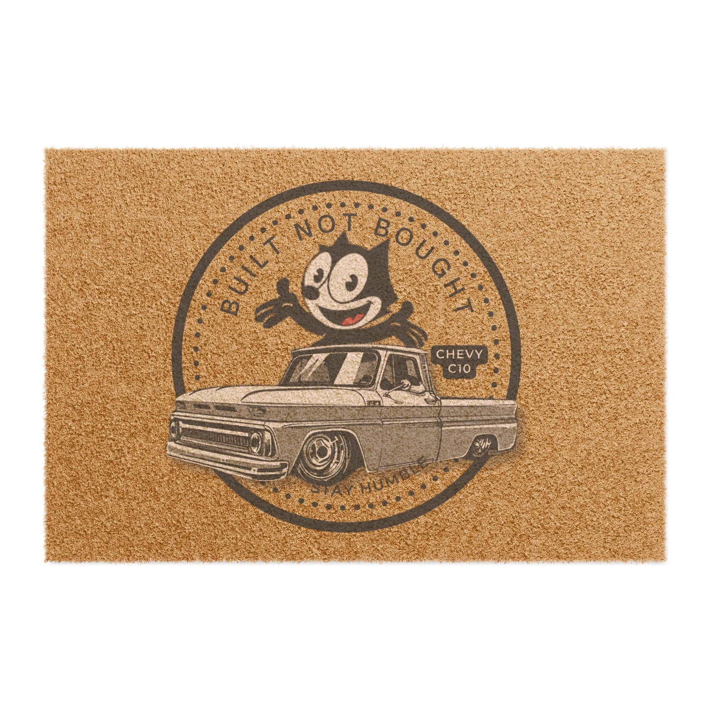 Coir doormat printed with a round Built Not Bought badge: a cartoon cat leaning on a lowered classic pickup truck, with Stay Humble along the bottom.