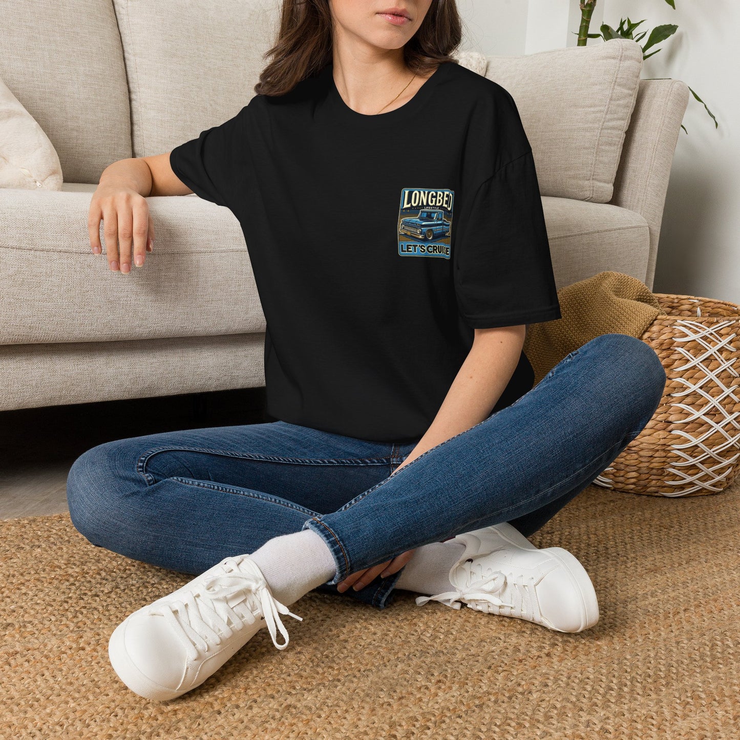 Woman seated wearing the black Longbed t-shirt with the small chest badge visible
