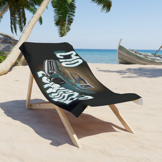 The towel draped over a wooden folding beach chair on sand, with palm trees and the sea behind it.